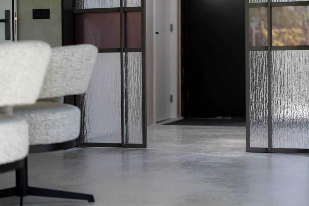Detailfoto van woonbetonvloer in eetkamer. Woonbetonvloer met de kleur 'Jennifer Sand'.
